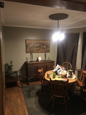 Un coin repas avec une table et des chaises en bois, un tableau au mur et un lustre.
