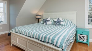 Een slaapkamer met een bed, nachtkastje, lamp en raam.