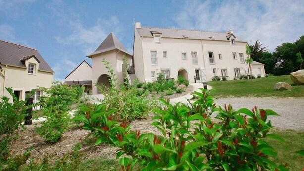 A large, multi-story building with a symmetrical facade, multiple windows, and a central entrance. - Appartement Cosy Equipée |  Accès Piscine (Le Tronchet)