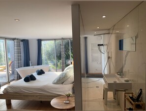 A modern bedroom with a large bed, a bathtub, and a glass-enclosed shower area.