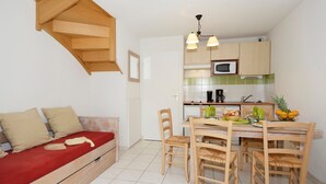 Een compacte keuken met houten kastjes, een magnetron, en een zithoek met een tafel en stoelen.