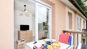 Een balkon met een ontbijtje gedekt, een televisie en een houten kast.