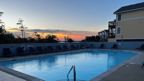 A swimming pool with lounge chairs and a view of the sunset. - Cozy 3br cottage on sound side near beach (Kill Devil Hills)