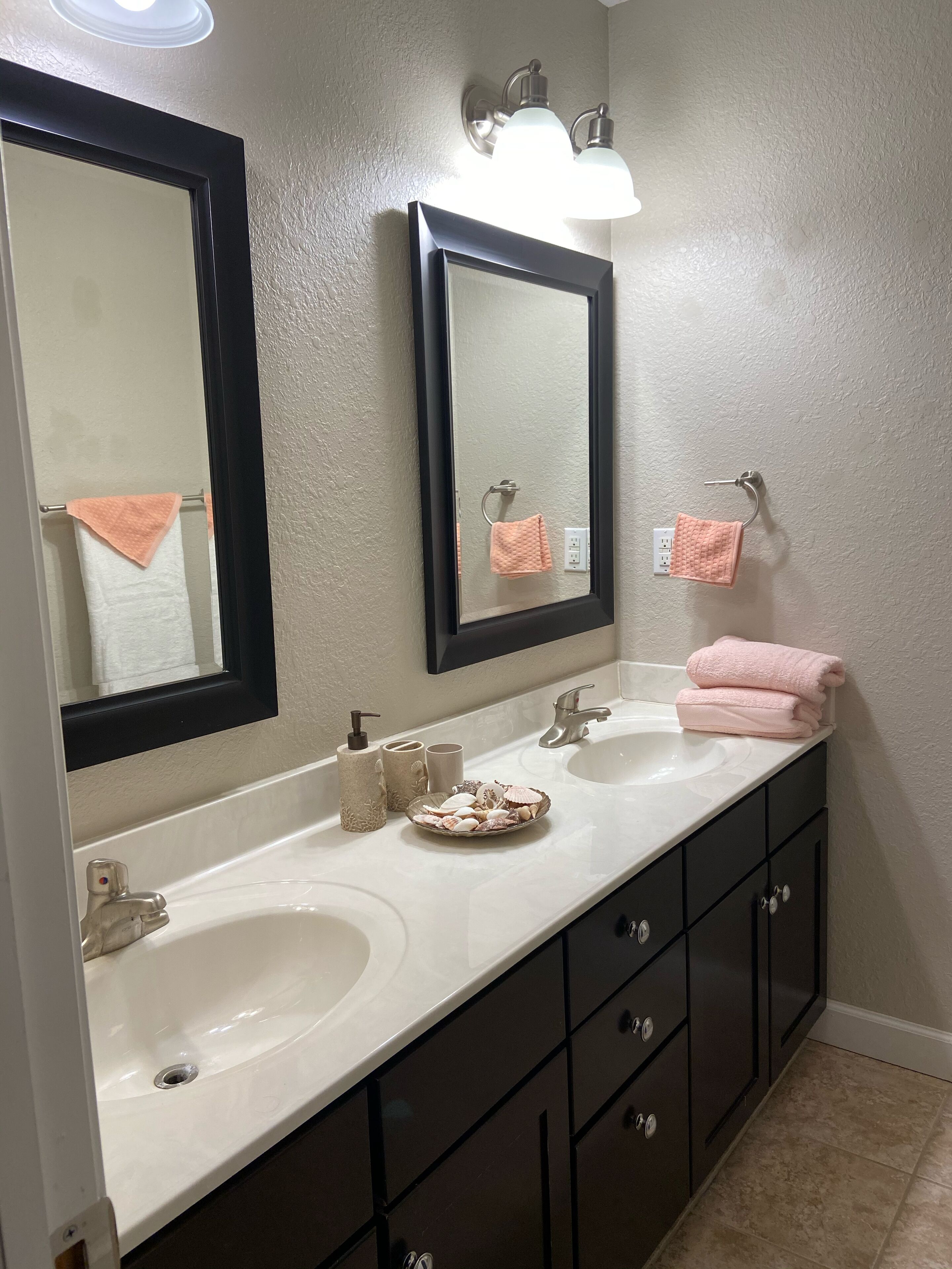 A bathroom with two sinks, a large mirror, a towel rack, and a vanity with drawers.