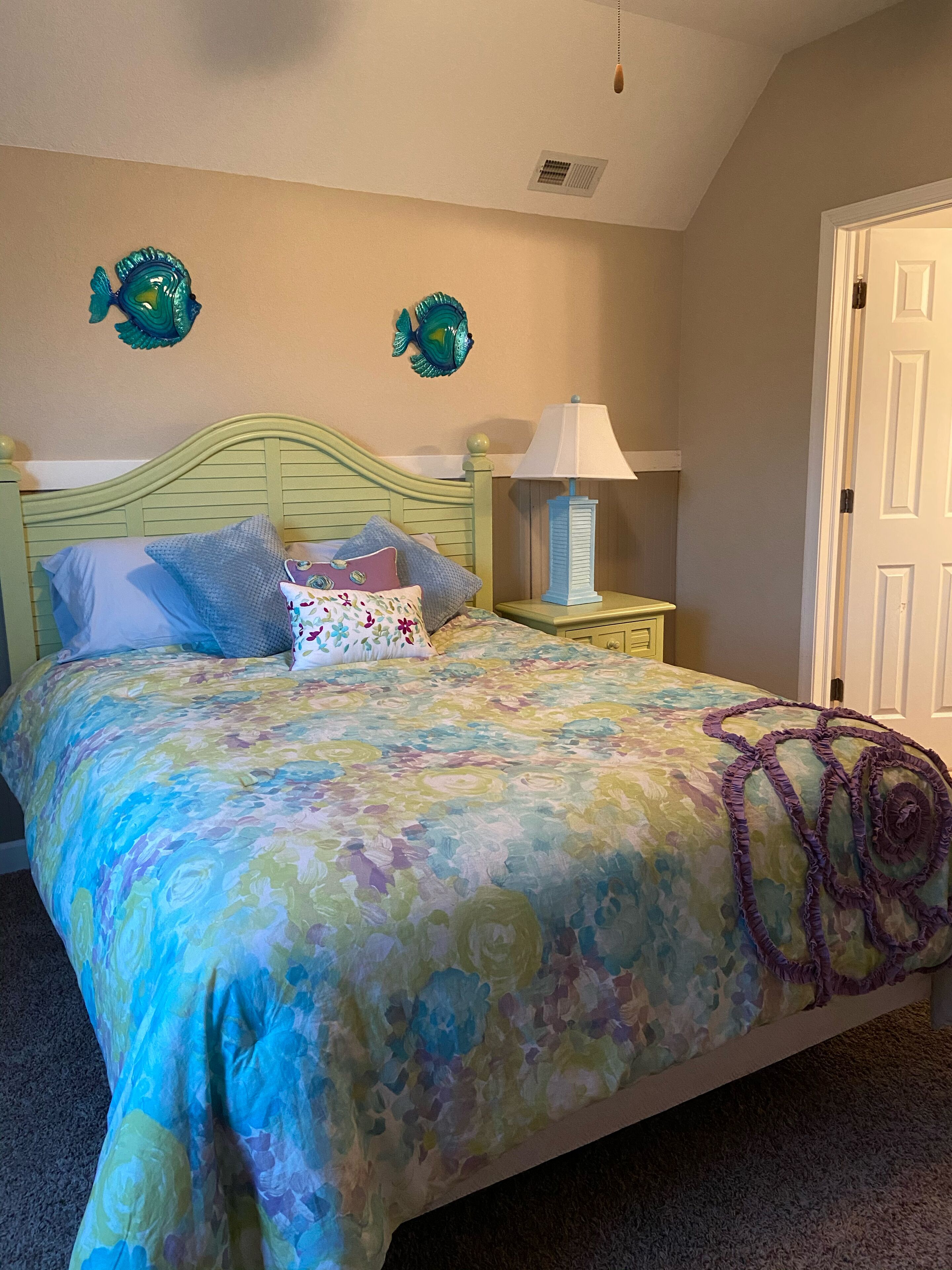 Une chambre à coucher comprenant un lit, une table de chevet, une lampe et des décorations murales représentant des poissons.