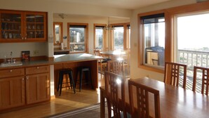 A spacious kitchen with wooden cabinets, a large island, and a dining area with wooden chairs.