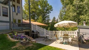 Un patio trasero con terraza, parrilla y zona de estar al aire libre.