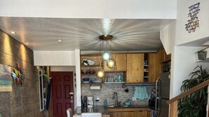 A modern kitchen with marble flooring, wooden cabinets, and a central island. - Full Ocean View! Prime Kihei Location!  (Kihei)