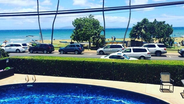 A swimming pool with a view of the beach and parked cars. - Full Ocean View! Prime Kihei Location!  (Kihei)