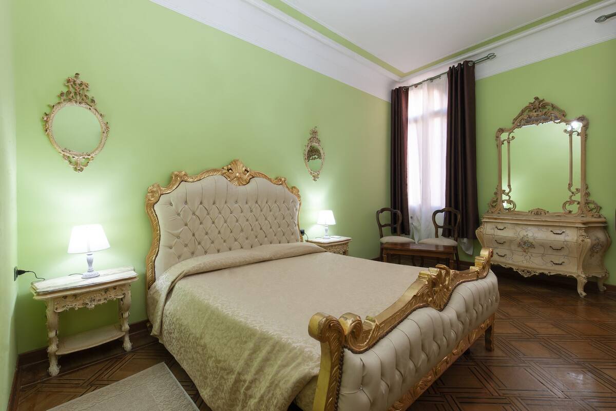 Une chambre à coucher avec un grand lit, deux tables de chevet, une commode et un miroir.