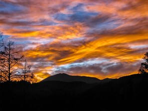 Uma cordilheira em silhueta contra um céu poente vibrante.