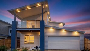 A modern two-story house with a garage, a balcony, and a well-lit entrance.