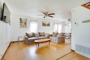 A living room with a wooden floor, two sofas, a coffee table, and a ceiling fan.
