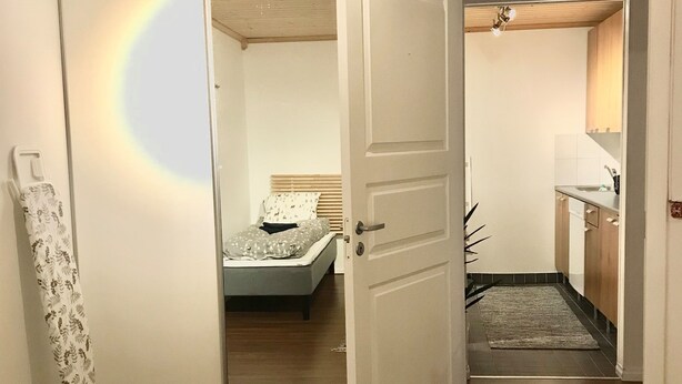 Ein Zimmer mit einem Bett, einem Spiegel, einem Kleiderschrank und einer kleinen Küchenzeile.