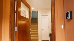Une porte en bois donne sur un couloir recouvert de moquette, avec un escalier en arrière-plan.