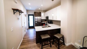Une cuisine moderne dotée d’un îlot central, de meubles en bois foncé et d’un réfrigérateur en acier inoxydable.