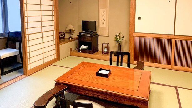 Una habitación japonesa tradicional con suelo de tatami, una mesa de madera baja y un panel shoji.