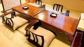 Comedor tradicional japonés con una mesa y sillas de madera, suelo de tatami y un shoji al fondo.