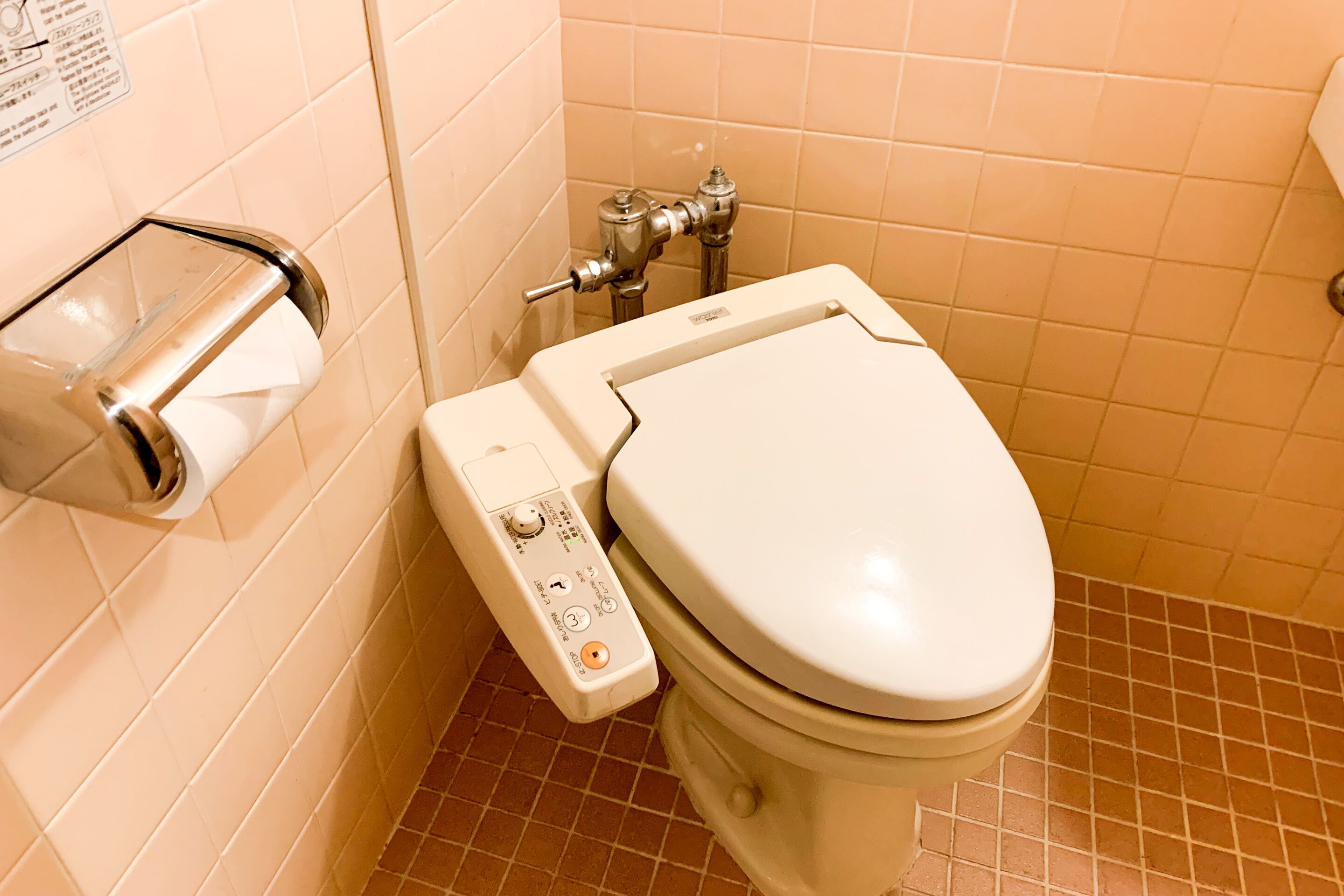 A toilet with a flush handle and a paper towel dispenser.