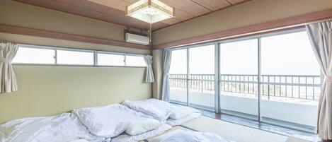 Habitación de hotel con una cama grande, ventilador de techo y vista al mar a través de la ventana.