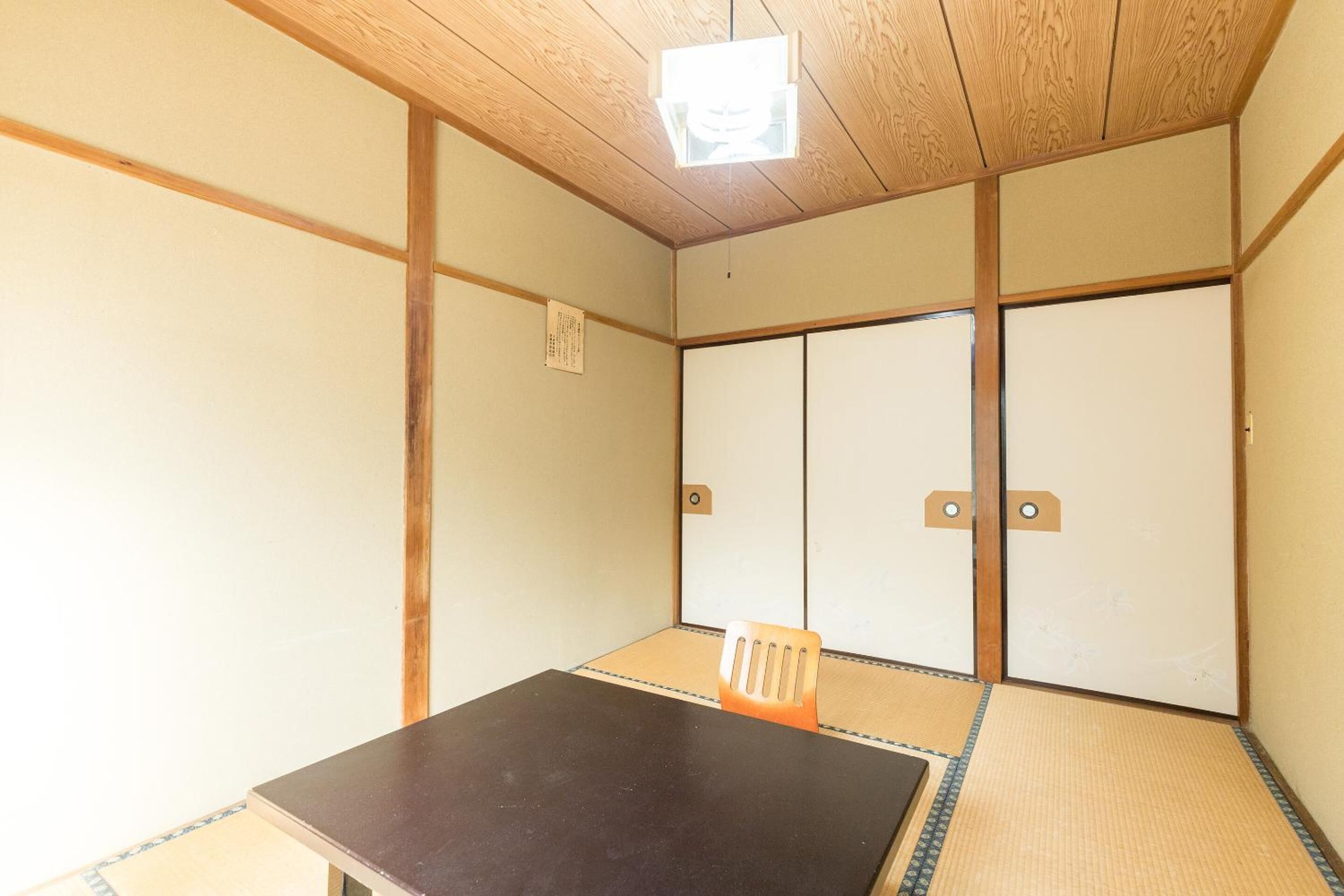 Una habitación japonesa tradicional con suelo de tatami, una mesa baja y puertas correderas.