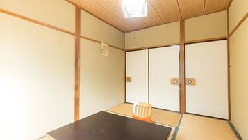 Una habitación japonesa tradicional con suelo de tatami, una mesa baja y puertas correderas.