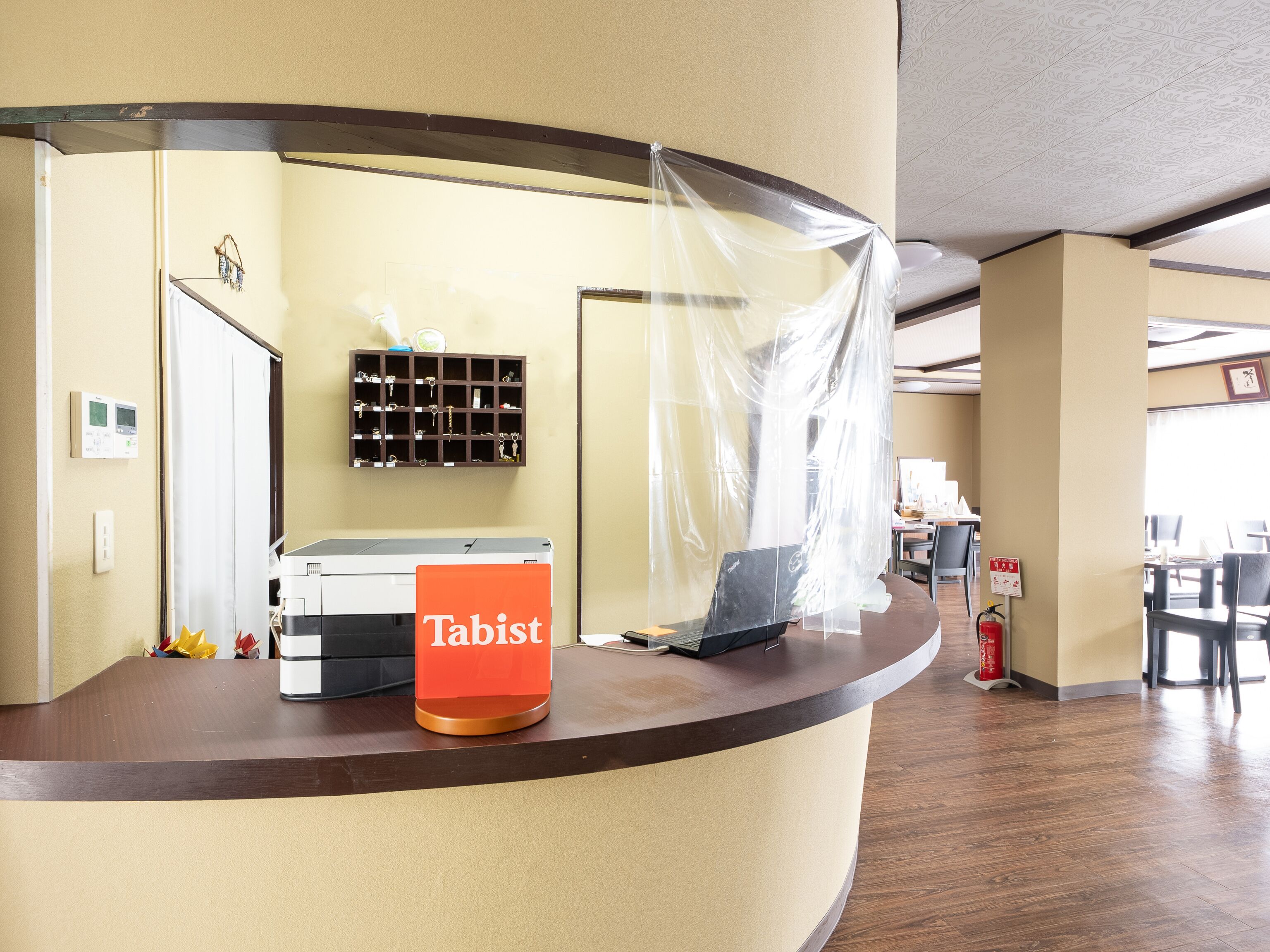 A reception desk with a 'Tabist' sign, a key rack, and a fire extinguisher.