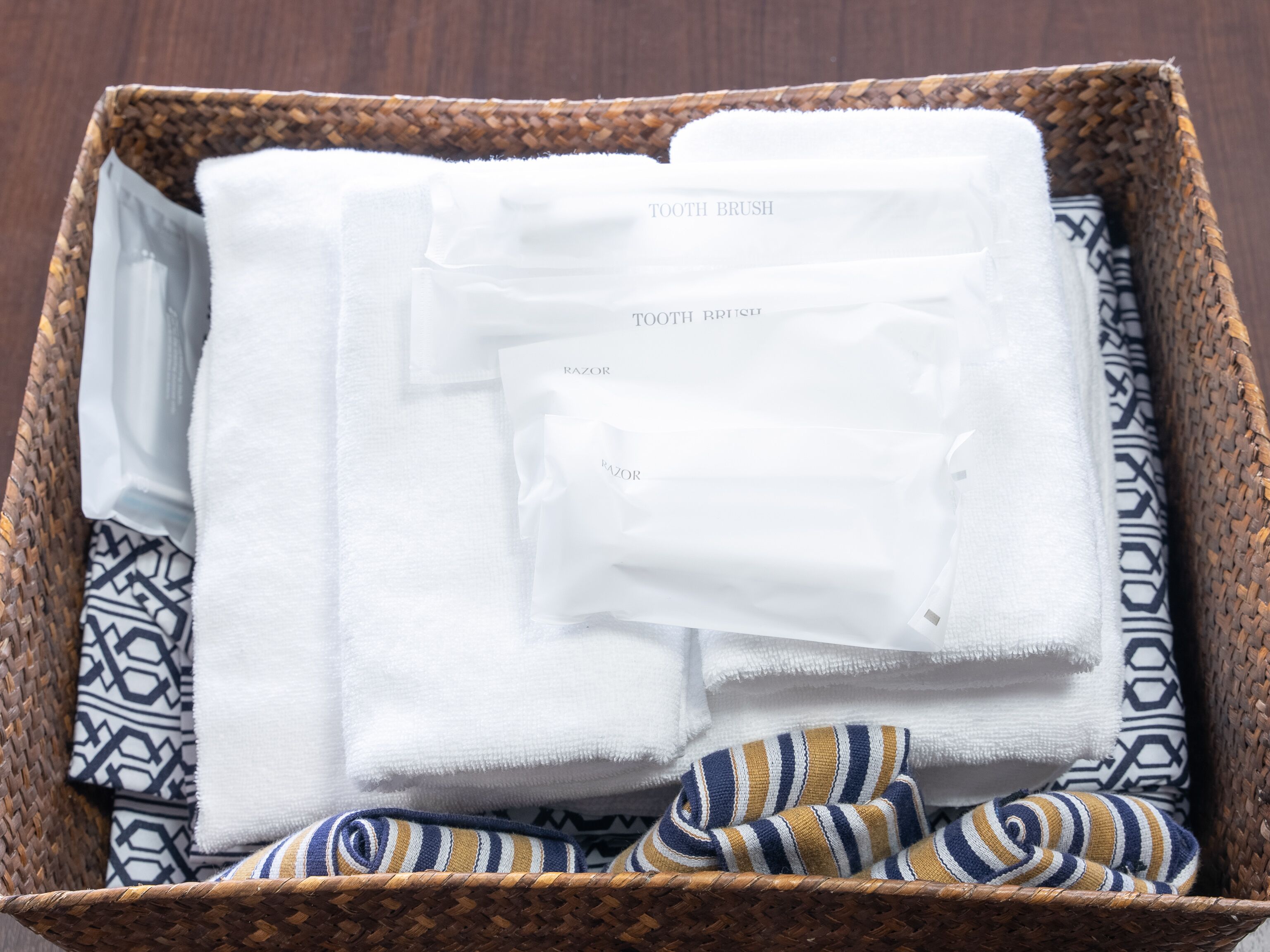 A wicker basket containing neatly folded white towels and a striped cloth.