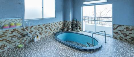A swimming pool with a tiled floor and walls, large windows, and a brick pattern on the lower walls.