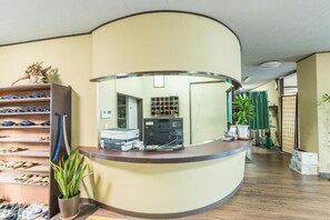 Welcome to our reception area, featuring a curved reception desk, a large mirror, and a potted plant.