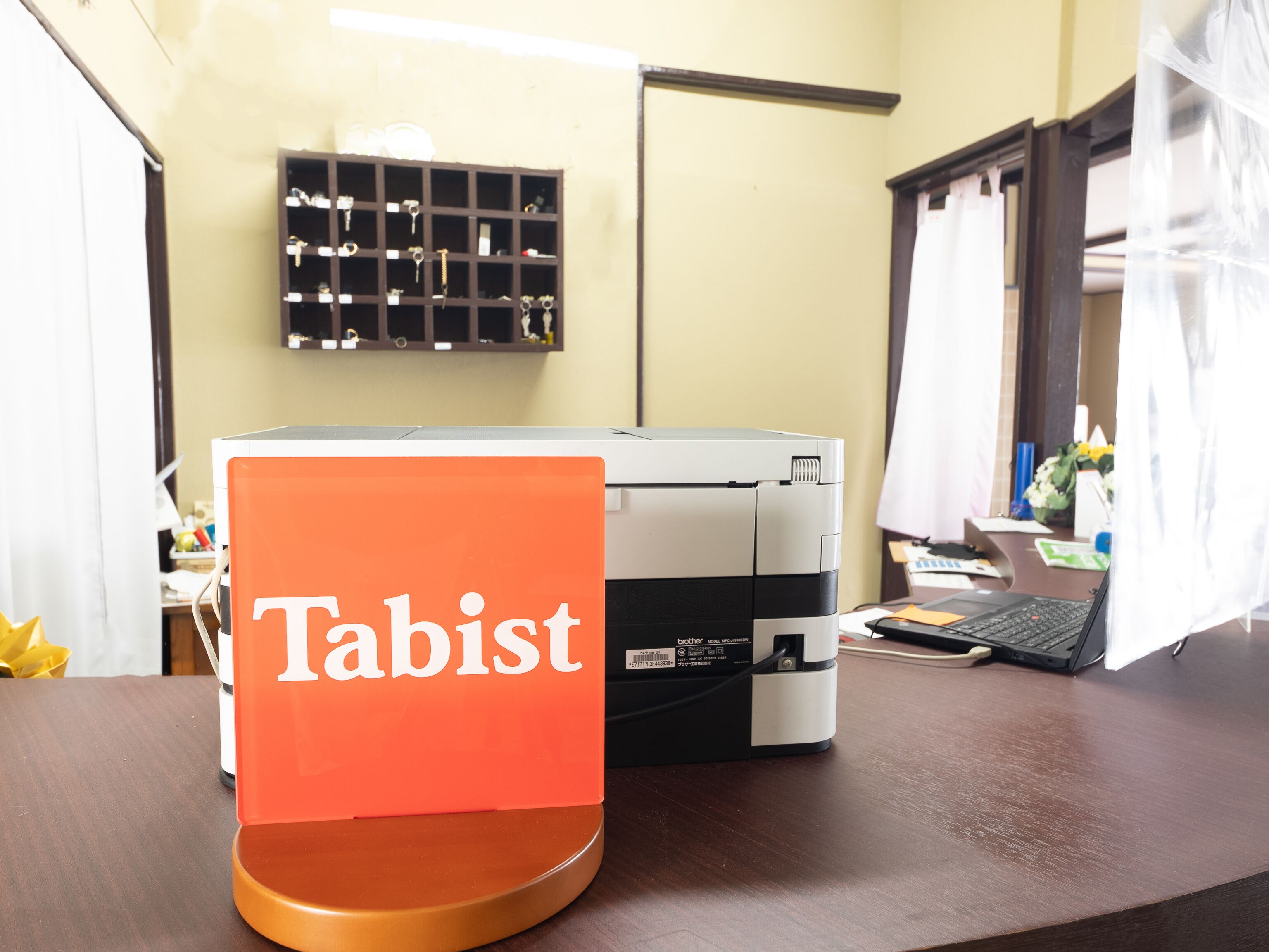 A printer on a desk with a sign reading "Tabist" in front of it.