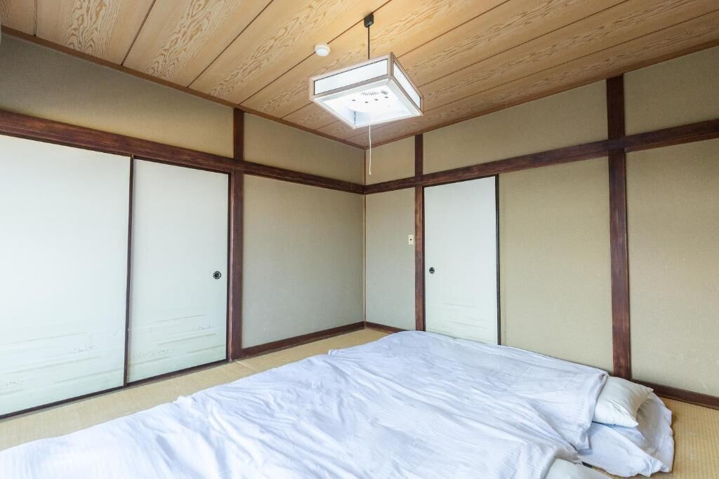 A room with a bed, wooden ceiling, and sliding doors.
