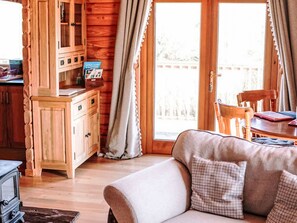 L’intérieur chaleureux d’un chalet avec des murs en bois, un meuble en bois, un canapé agrémenté de coussins à carreaux et une table à manger.