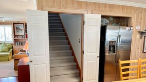 A kitchen with a stainless steel refrigerator, a wooden dining table, and a staircase leading to another room. - Old Pamlico Inn Site:  Large waterfront home with dock, amazing views (Ocracoke)