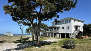 A two-story house with a porch, a staircase, and a view of the beach. - Old Pamlico Inn Site:  Large waterfront home with dock, amazing views (Ocracoke)