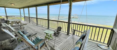 A wooden deck with seating and a view of the ocean.