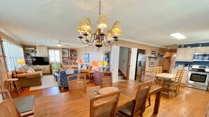 A spacious living room with a wooden dining table and chairs, a TV, and a chandelier. - Old Pamlico Inn Site:  Large waterfront home with dock, amazing views (Ocracoke)