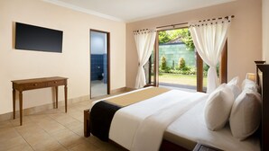 A hotel room with a bed, a desk, and a TV. - Villa Sotra Description (Denpasar)