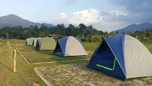 A row of dome-shaped tents in a campsite with a mountainous backdrop. - The Red Cabanon (Janda Baik)