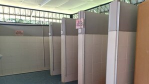 A row of single-occupancy restrooms with privacy partitions and a sign requesting help to keep the toilet clean. - The Red Cabanon (Janda Baik)
