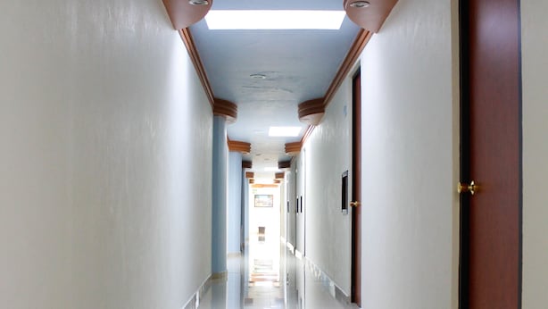 Un pasillo largo y estrecho con suelo pulido, paredes blancas y detalles de madera.