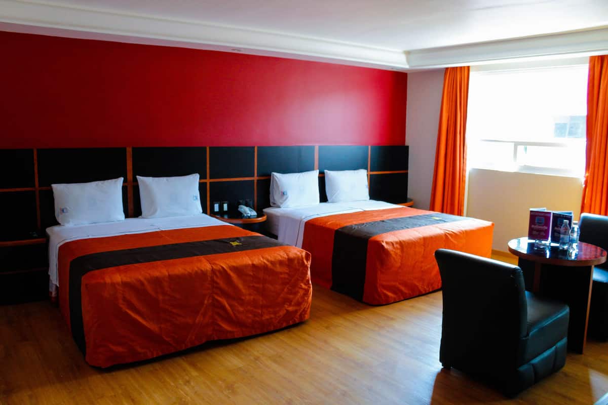 Une chambre d’hôtel avec deux lits, un bureau et une chaise.