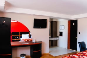 Ein Hotelzimmer mit Bett, Schreibtisch, Fernseher und einer Tür.