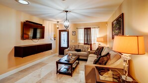 A living room with a flat-screen TV, a sofa, a coffee table, and a lamp. - Home Away From Home   (Boynton Beach)