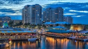 A waterfront hotel with multiple high-rise buildings, a marina, and outdoor dining areas. - Home Away From Home   (Boynton Beach)
