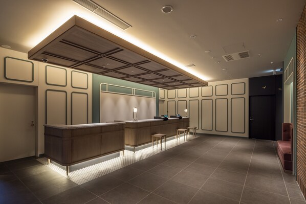 A modern hotel lobby with a reception desk, seating area, and a large window.