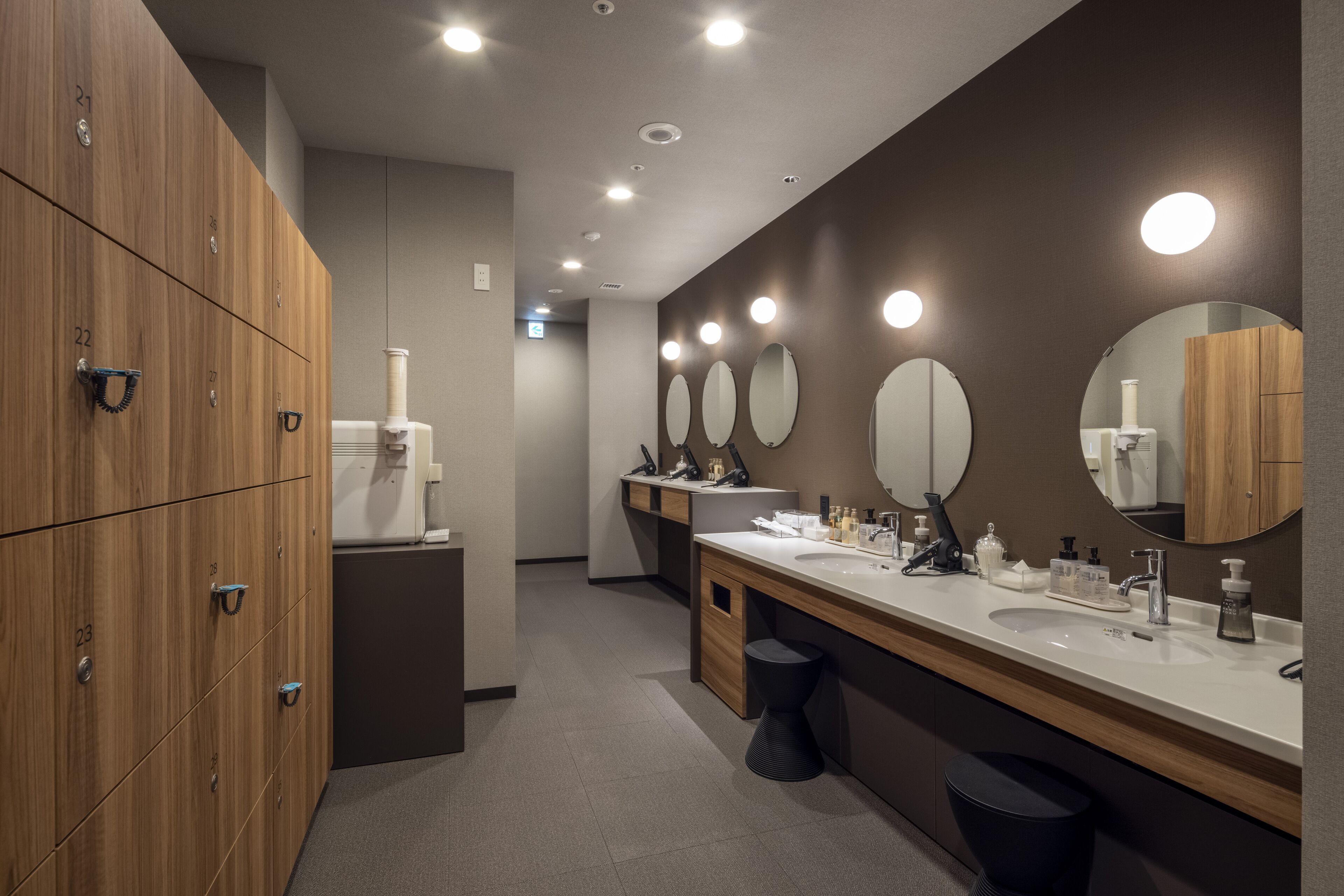 A modern bathroom with wooden lockers, multiple sinks, and mirrors.