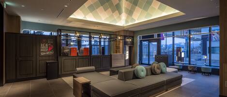 A modern lounge area with a large seating area, a coffee shop, and large windows offering a view of the city.