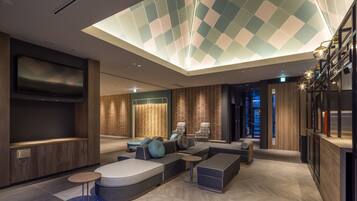 Un'area lounge moderna con ampie sedute, una televisione a schermo piatto e un soffitto con finestra a lucernario.