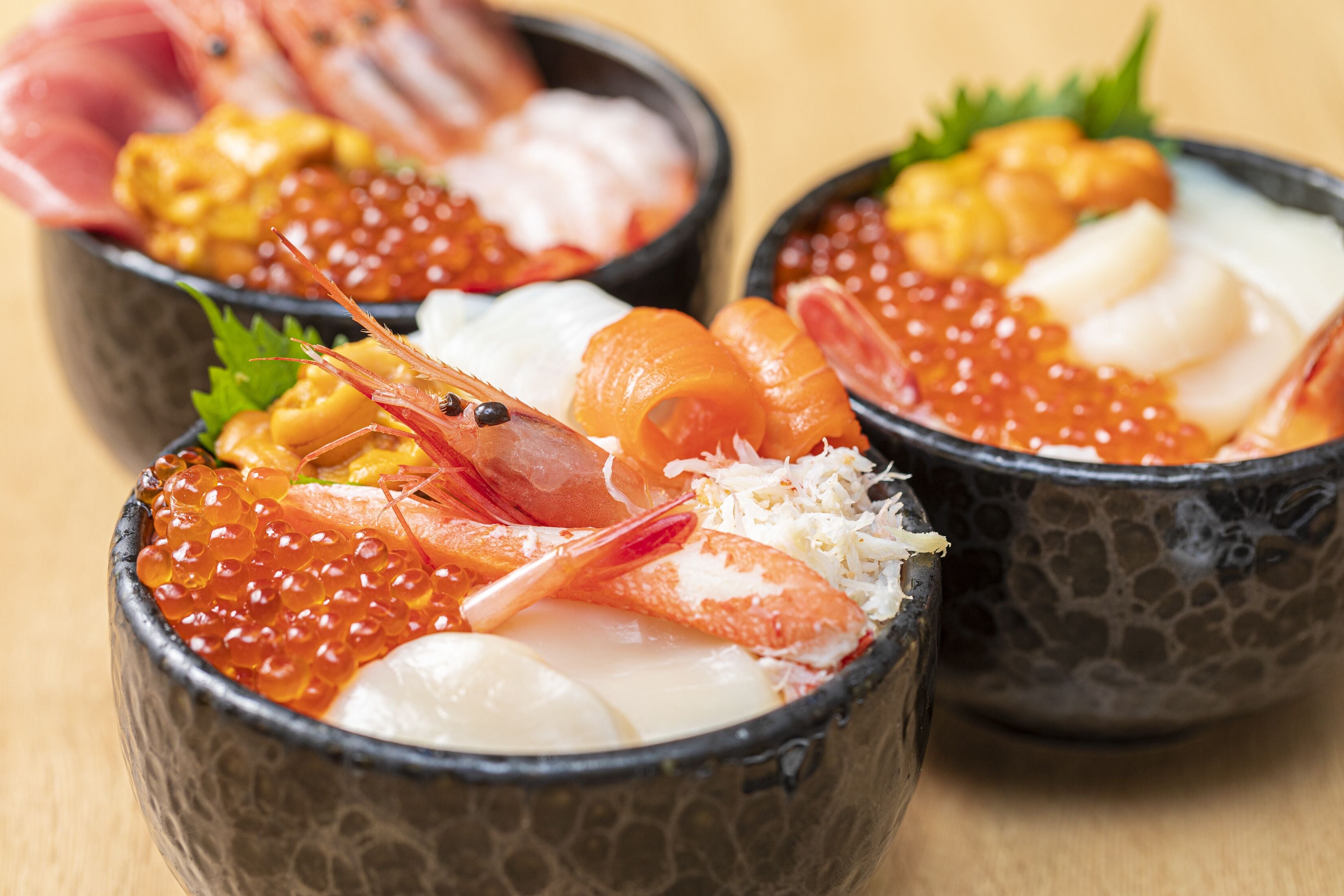 Three bowls of sushi with various toppings.